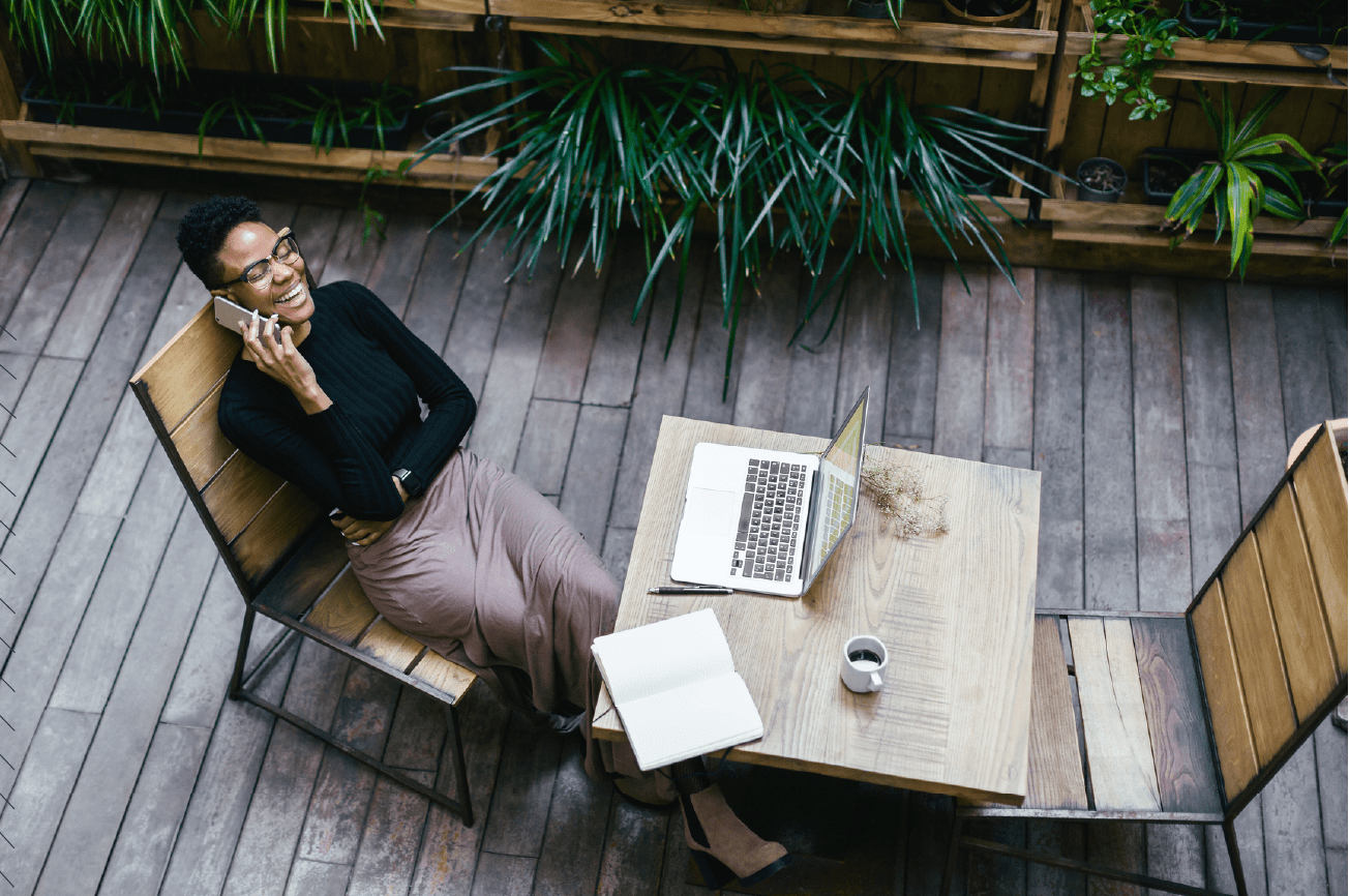 A woman sitting on a patio with her laptop and phone, setting up a professional email