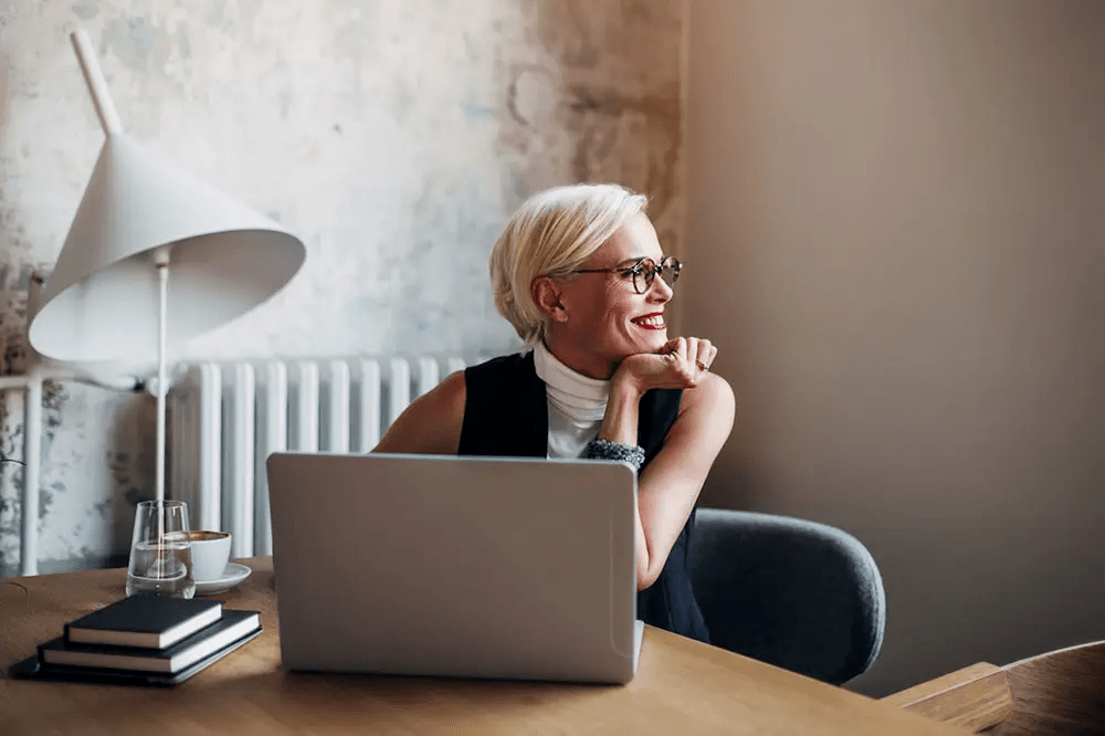 Woman smiling out window with laptop