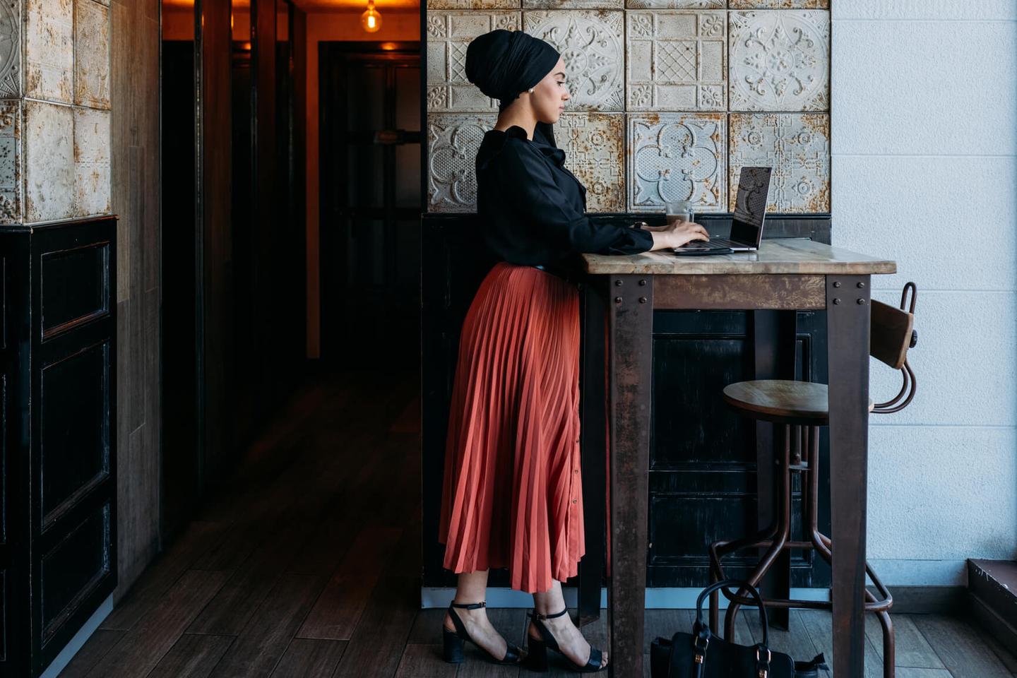 A woman standing and typing on her laptop