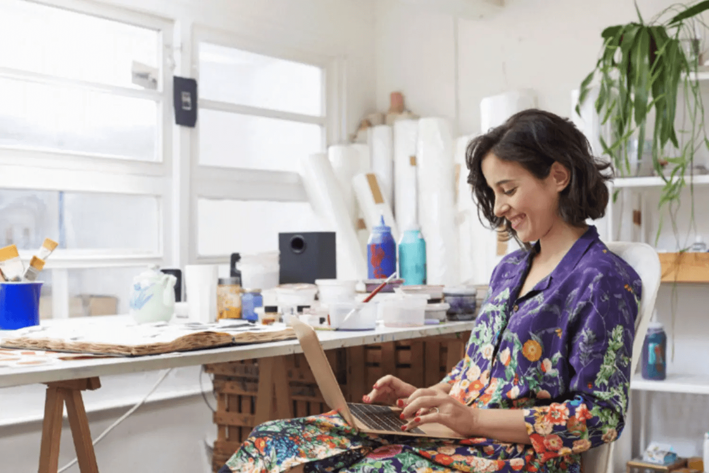 Woman in a colorful shirt happily working on her laptop